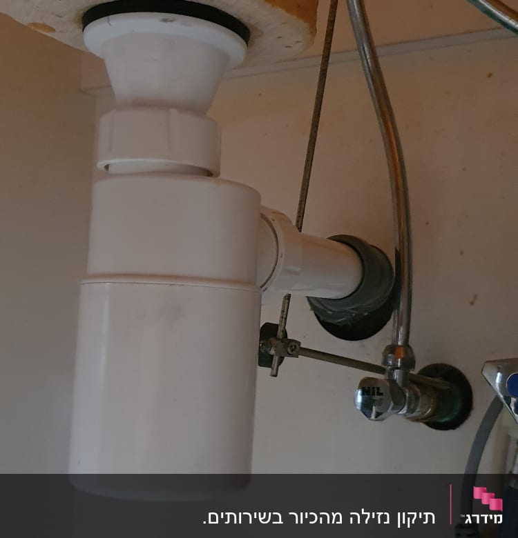 צינור ניקוז לבן מתחת לכיור עם ברזים